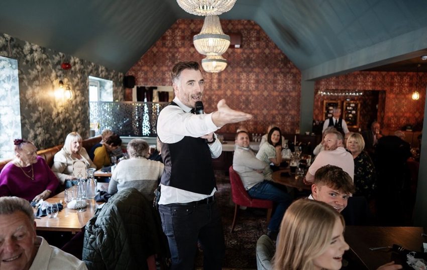 Matthew performing as a singing waiter among seated guests in a decorated venue